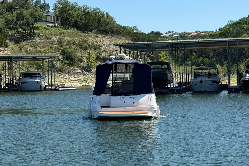 Slide: The Image of 2006 Sea Ray Sundancer 320 yacht docked on a serene lake with surrounding greenery. - 17
