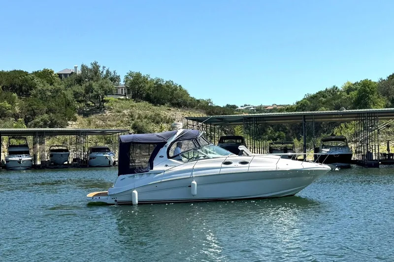 Slide: The Image of 2006 Sea Ray Sundancer 320 yacht on a serene lake with docked boats in the background. - 2