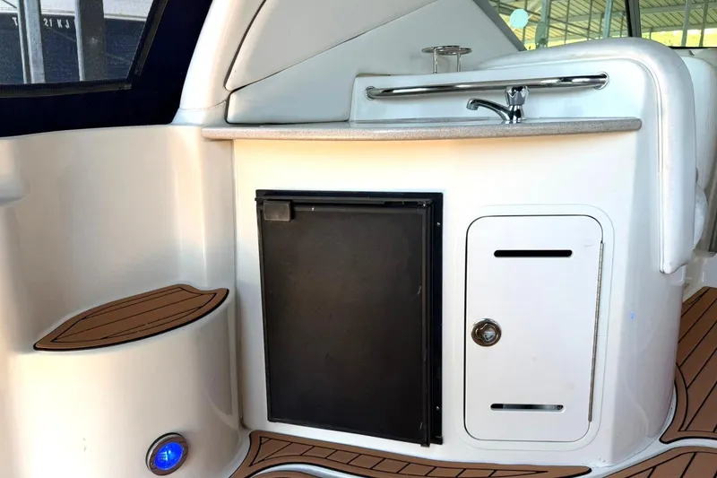 Slide: The Image of 2006 Sea Ray Sundancer 320 interior with kitchenette, featuring a sink and mini fridge. - 24