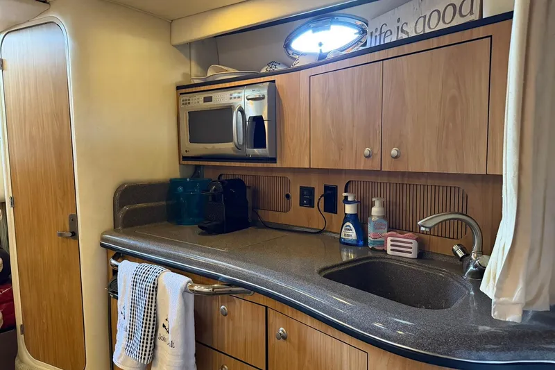 Slide: The Image of 2006 Sea Ray Sundancer 320 interior kitchen with microwave, sink, and wooden cabinets. - 42