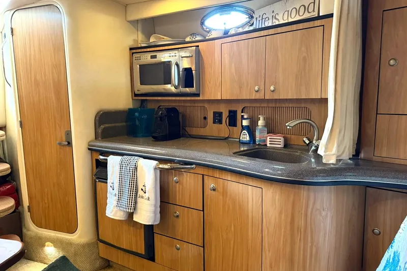 Slide: The Image of 2006 Sea Ray Sundancer 320 interior kitchen with wooden cabinets, microwave, and sink. - 43