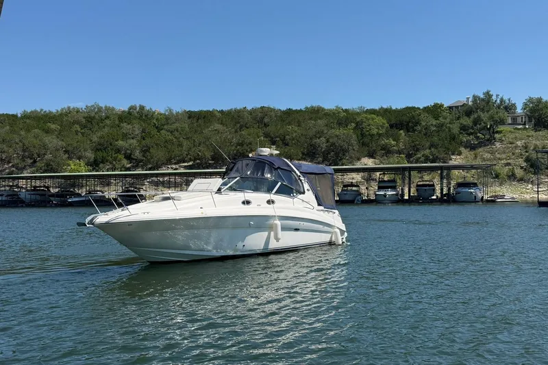 Slide: The Image of 2006 Sea Ray Sundancer 320 yacht on a serene lake with lush green shoreline. - 8