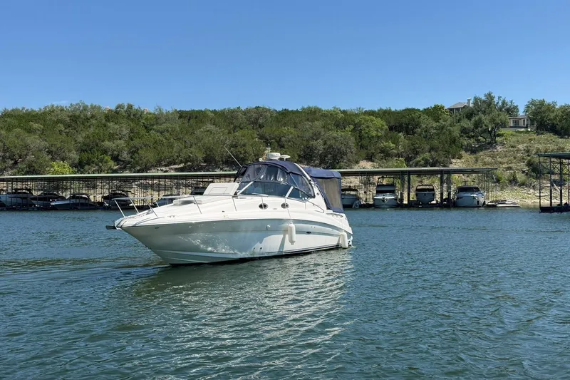 Slide: The Image of 2006 Sea Ray Sundancer 320 cruising on a serene lake with lush greenery backdrop. - 9