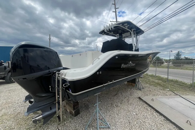 Slide: The Image of 2017 NauticStar 28 XS boat on stands, black hull, overcast sky background. - 13