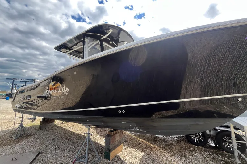 Slide: The Image of 2017 NauticStar 28 XS boat on stands, glossy black hull, cloudy sky background. - 2