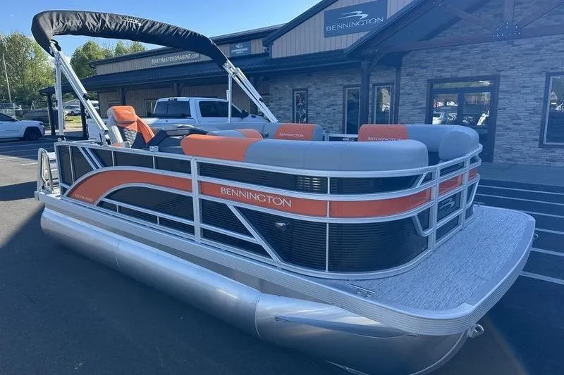Slide: The Image of 2026 Bennington S L-Bench 168 SLJ pontoon boat with orange accents, parked outside dealership. - 10