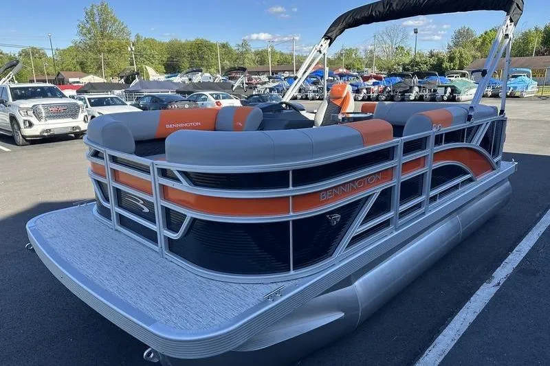 Slide: The Image of 2026 Bennington S L-Bench 168 SLJ pontoon boat with orange accents in a parking lot. - 7