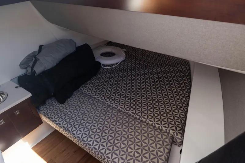 Slide: The Image of 2022 Chaparral 300 OSX cabin interior with patterned bedding and storage space. - 11