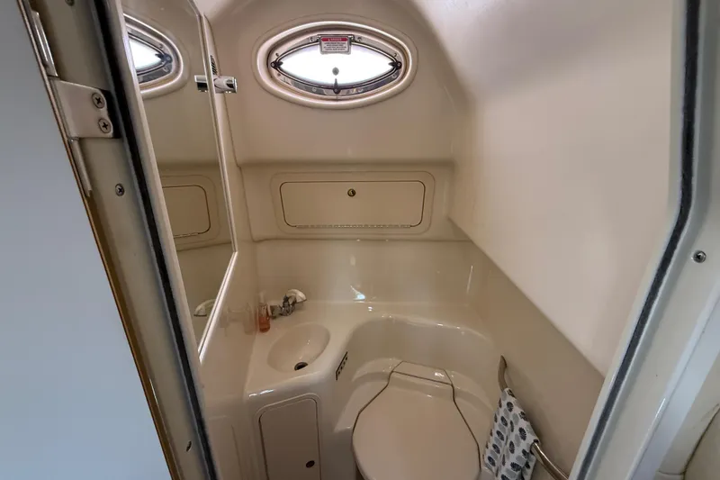Slide: The Image of Compact bathroom in 2000 Sea Ray 410 Sundancer yacht, featuring sink, toilet, and porthole window. - 50