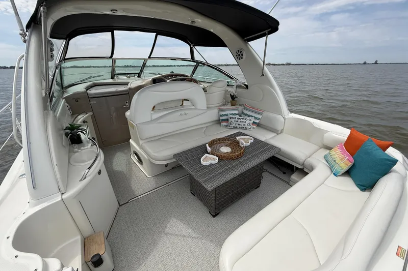 Slide: The Image of 2000 Sea Ray 410 Sundancer yacht interior with white seating and decorative pillows on a calm lake. - 6