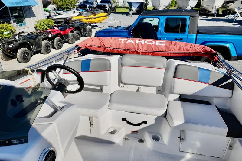 Slide: The Image of 2024 Tahoe T18 boat interior with steering wheel and seating, parked near ATVs and a blue truck. - 3