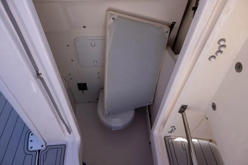 Slide: The Image of 2023 Robalo 266 Cayman boat interior with compact toilet and storage area. - 14
