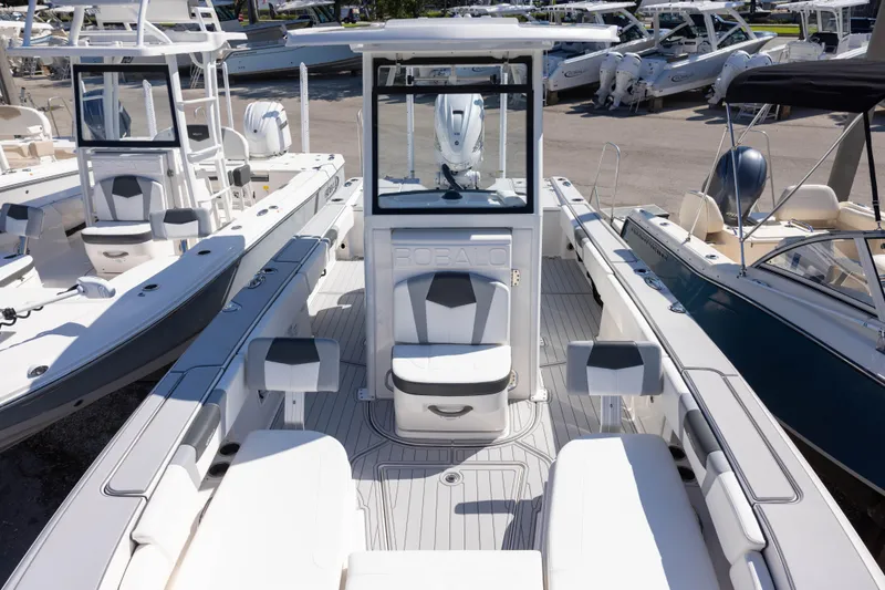 Slide: The Image of 2023 Robalo 266 Cayman boat interior with seating and console, docked among other boats. - 16