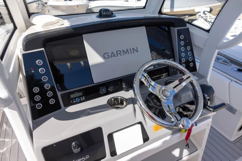 Slide: The Image of 2023 Robalo 266 Cayman boat dashboard with Garmin navigation system and chrome steering wheel. - 8