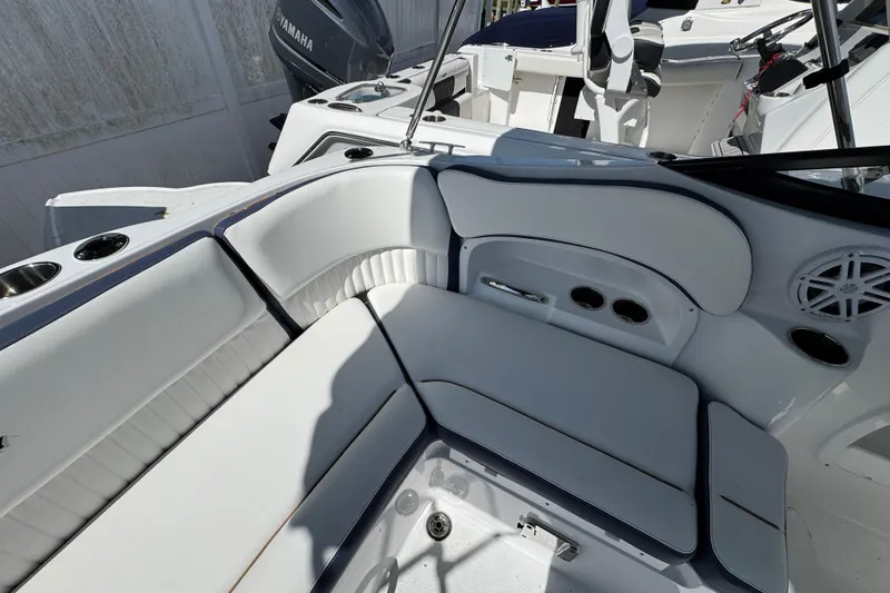 Slide: The Image of Interior seating of a 2026 Stingray 211 DC boat, featuring white upholstery and cup holders. - 6
