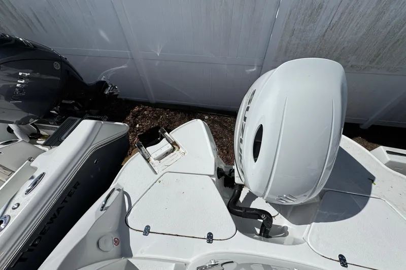 Slide: The Image of 2026 Stingray 211 DC boat with Suzuki outboard motor, parked beside a Tidewater boat. - 9