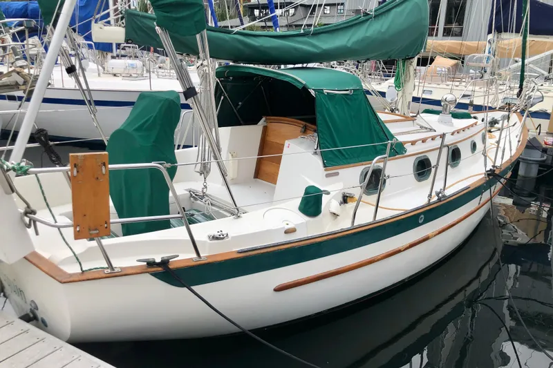 Slide: The Image of 1988 Pacific Seacraft 31 sailboat docked, featuring green covers and wooden accents. - 1