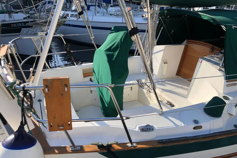 Slide: The Image of 1988 Pacific Seacraft 31 sailboat cockpit with green covers, docked at a marina. - 2