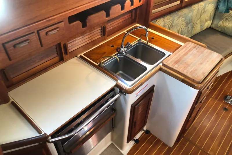 Slide: The Image of 1988 Pacific Seacraft 31 yacht kitchen with dual sinks, wooden cabinetry, and cutting board. - 6