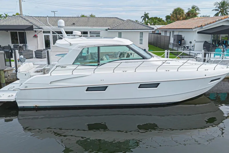 The Image of 2012 Cruisers Yachts 48 Cantius docked by waterfront homes, showcasing sleek design. - 0