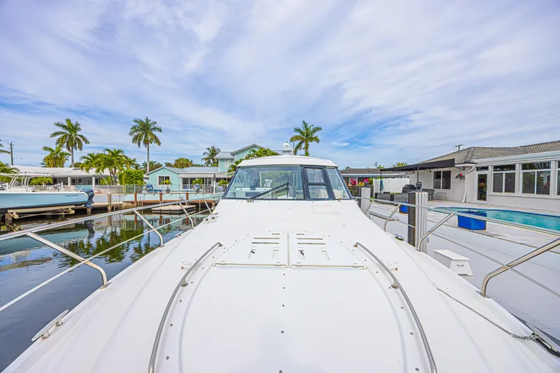 Slide: The Image of 2012 Cruisers Yachts 48 Cantius docked near waterfront homes and palm trees. - 10