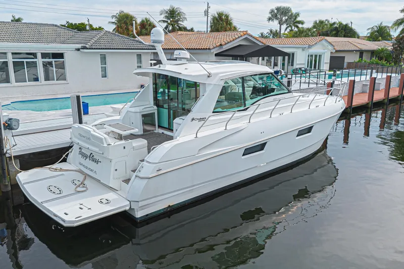 Slide: The Image of 2012 Cruisers Yachts 48 Cantius docked by waterfront homes. - 2