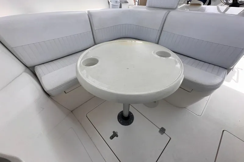 Slide: The Image of 2007 Intrepid 310 Walkaround boat interior with round table and cushioned seating. - 13