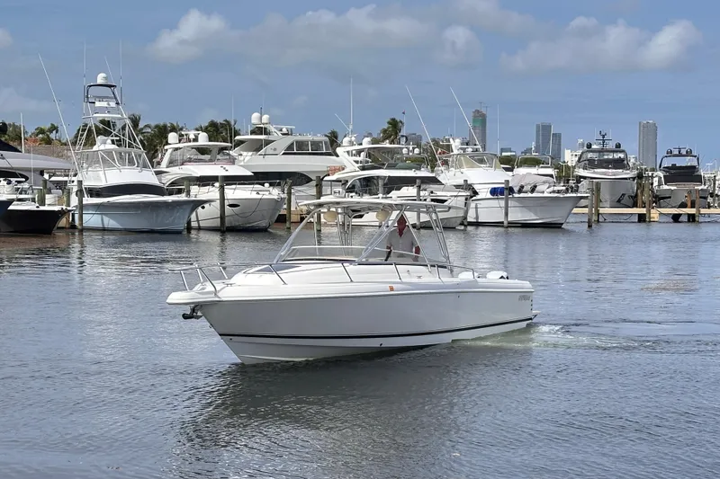 Slide: The Image of 2007 Intrepid 310 Walkaround boat cruising in a marina with yachts in the background. - 2