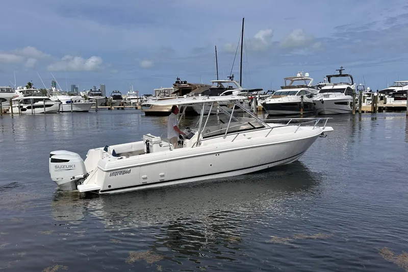 Slide: The Image of 2007 Intrepid 310 Walkaround boat with Suzuki engine in a marina setting. - 22