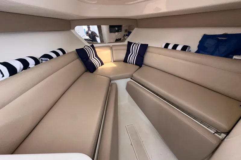 Slide: The Image of Interior of a 2007 Intrepid 310 Walkaround boat with beige seating and striped pillows. - 9