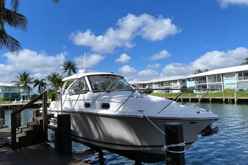 The Image of 2016 Pursuit OS 325 Offshore boat docked by waterfront homes under blue sky. - 0