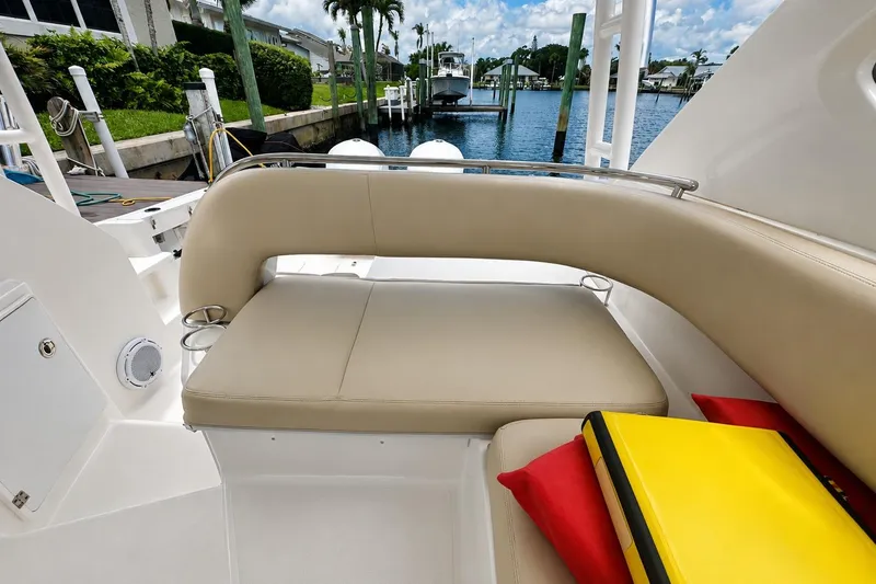 Slide: The Image of 2016 Pursuit OS 325 Offshore boat interior with beige seating and colorful cushions by the water. - 10