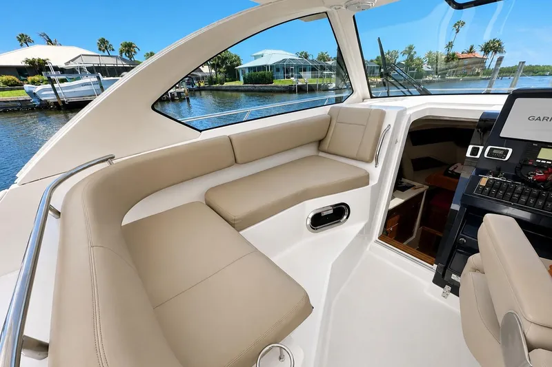 Slide: The Image of 2016 Pursuit OS 325 Offshore boat interior with beige seating and navigation equipment. - 11