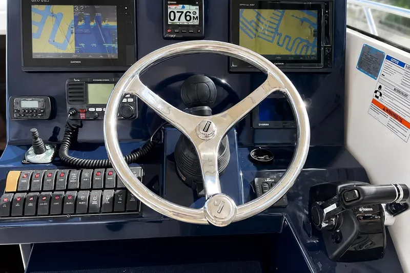 Slide: The Image of Steering wheel and controls of a 2016 Pursuit OS 325 Offshore boat cockpit. - 14