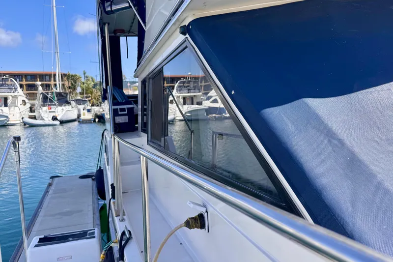 Slide: The Image of 1985 Californian 35 Motor Yacht docked in a marina, showcasing sleek design and blue canopy. - 11