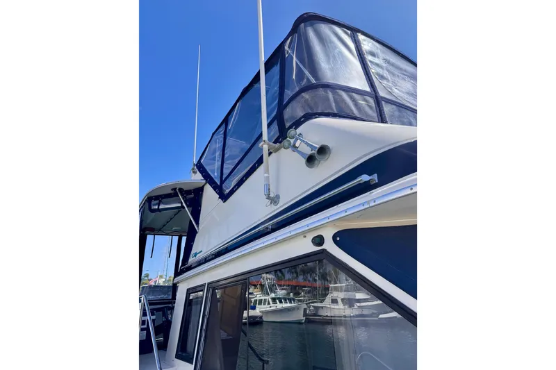 Slide: The Image of 1985 Californian 35 Motor Yacht with blue canopy, docked under clear sky. - 12