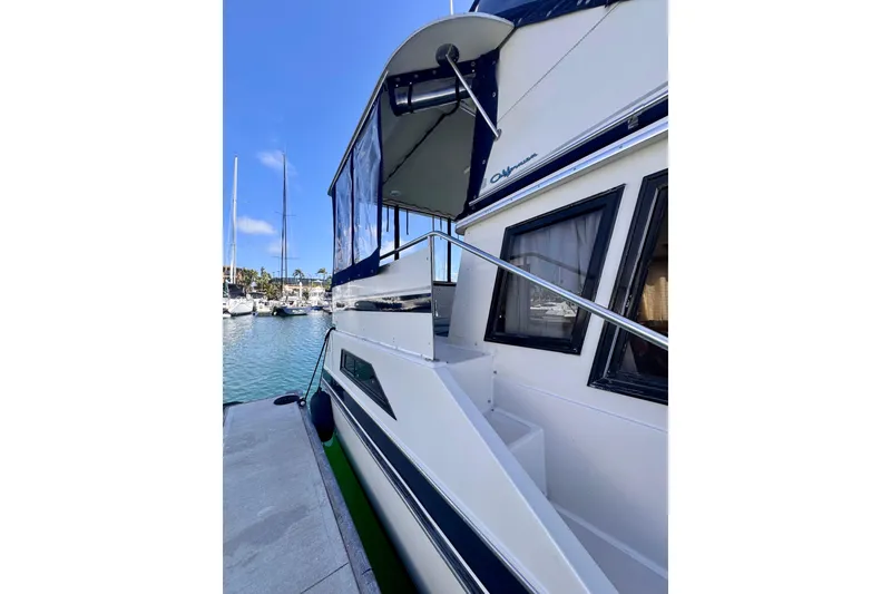 Slide: The Image of 1985 Californian 35 Motor Yacht docked at marina, showcasing sleek design and spacious deck. - 14