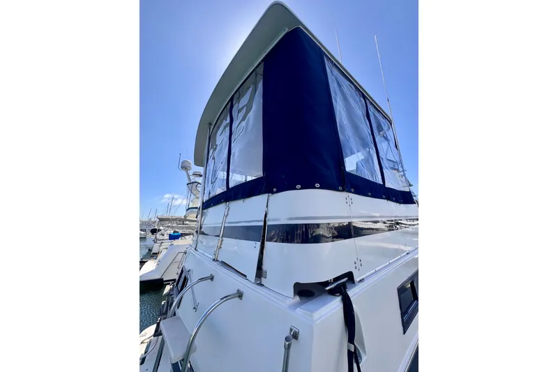 Slide: The Image of 1985 Californian 35 Motor Yacht with blue canopy, docked under clear sky. - 16
