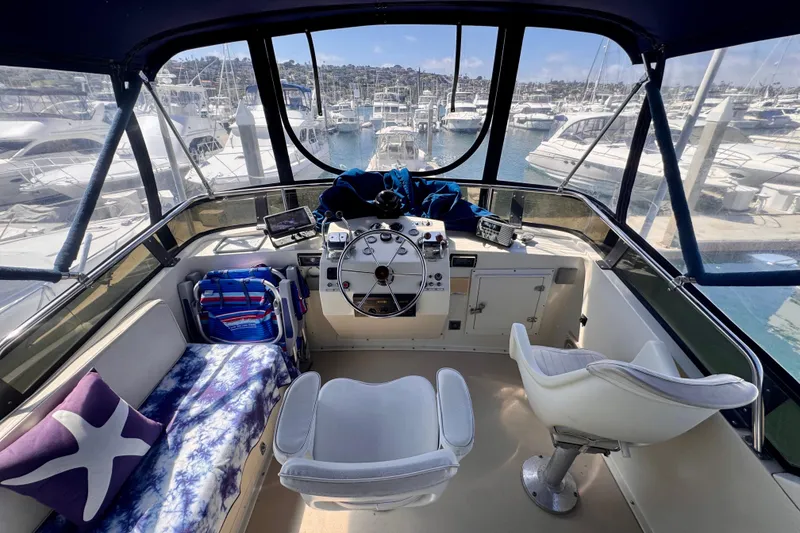 Slide: The Image of 1985 Californian 35 Motor Yacht helm with marina view, featuring comfortable seating and navigation equipment. - 28