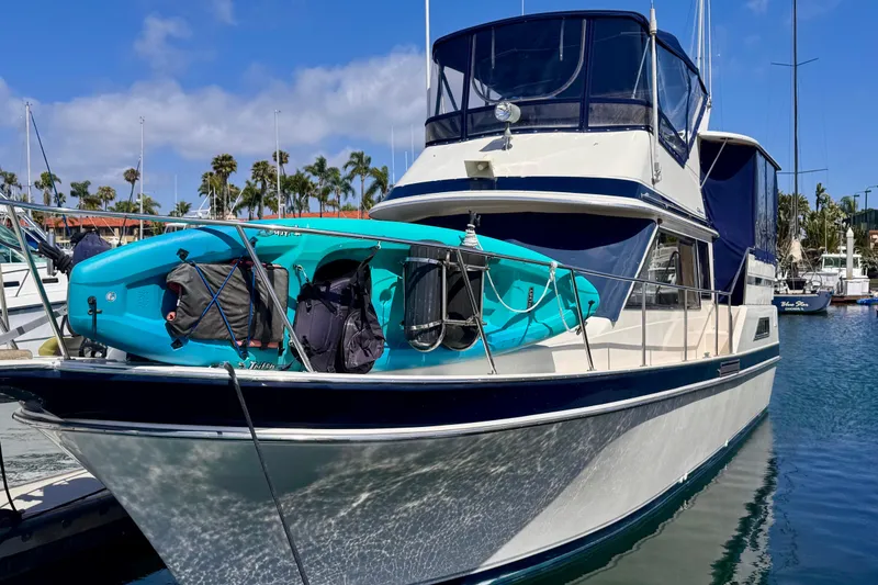 Slide: The Image of 1985 Californian 35 Motor Yacht docked with kayak on deck, sunny marina backdrop. - 3