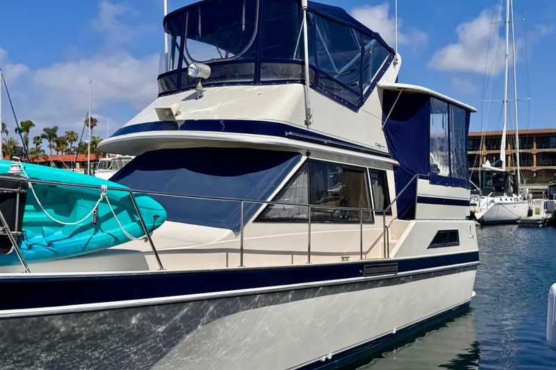 Slide: The Image of 1985 Californian 35 Motor Yacht docked, featuring blue accents and a kayak on deck. - 4