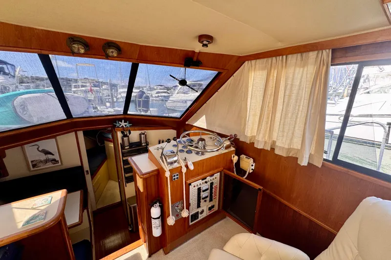 Slide: The Image of 1985 Californian 35 Motor Yacht interior helm with wooden paneling and marina view. - 48