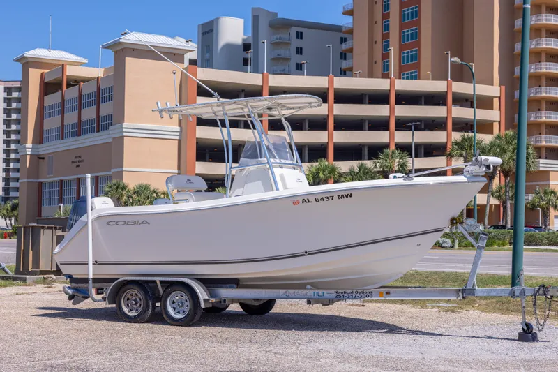 The Image of 2014 Cobia 214 Center Console boat on trailer, urban background. - 0