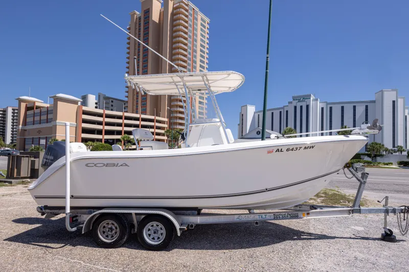 Slide: The Image of 2014 Cobia 214 Center Console boat on trailer, urban background, clear sky. - 14