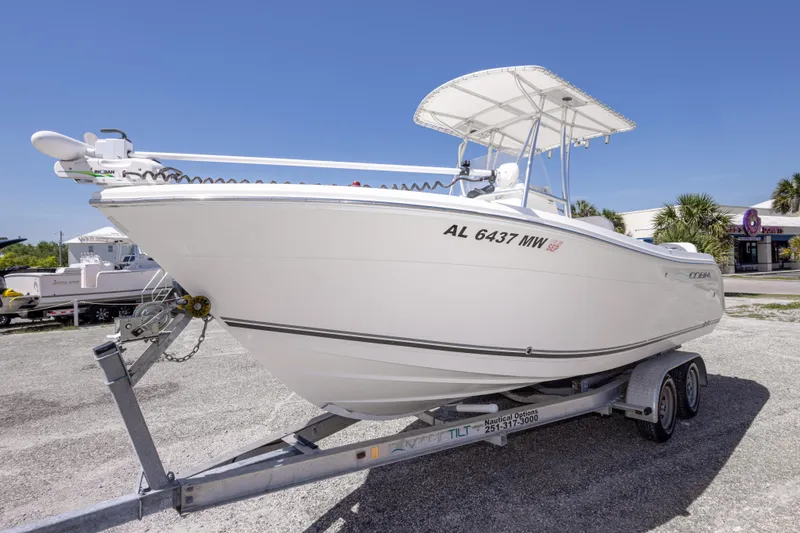 Slide: The Image of 2014 Cobia 214 Center Console boat on trailer, parked outdoors under clear blue sky. - 19