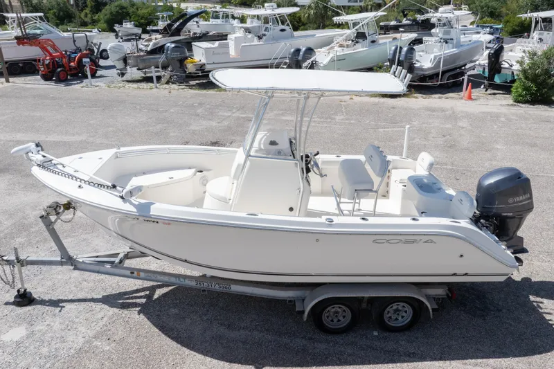 Slide: The Image of 2014 Cobia 214 Center Console boat on trailer, parked in a marina. - 2