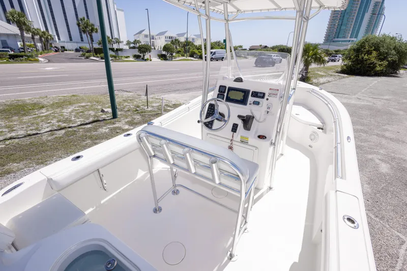 Slide: The Image of 2014 Cobia 214 Center Console boat with modern helm and seating, parked near a coastal road. - 23