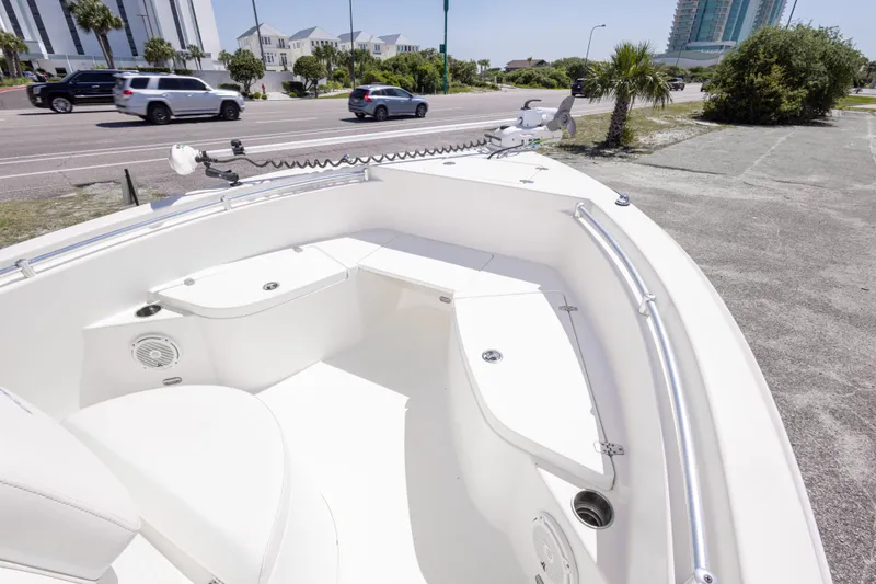 Slide: The Image of 2014 Cobia 214 Center Console boat interior with seating and storage, parked near a road. - 35
