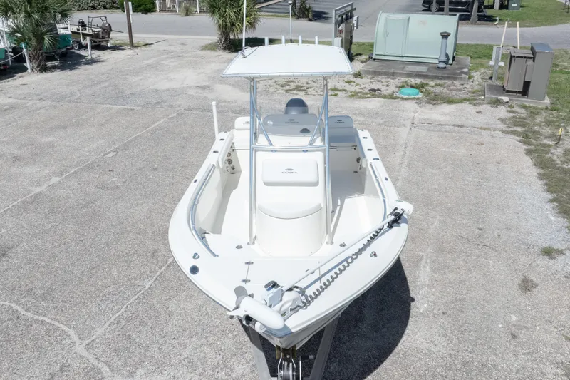 Slide: The Image of 2014 Cobia 214 Center Console boat parked on concrete, featuring a sleek design and T-top. - 4