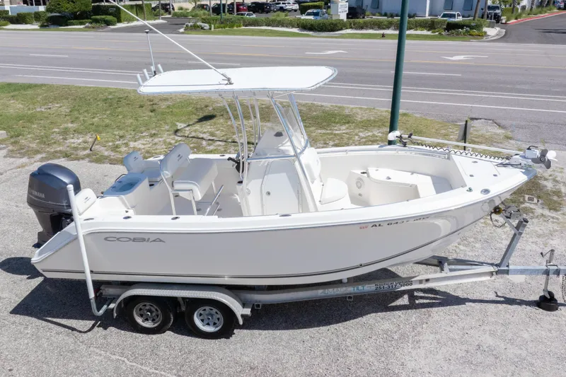 Slide: The Image of 2014 Cobia 214 Center Console boat on trailer, parked near a road. - 9